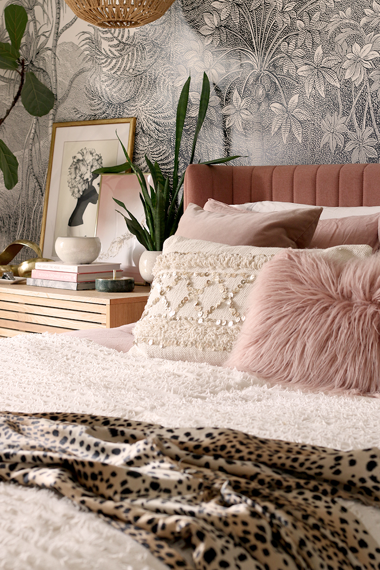 cream and pink bedding on bed with mongolian fur cushion and an animal print dressing gown on the foreground